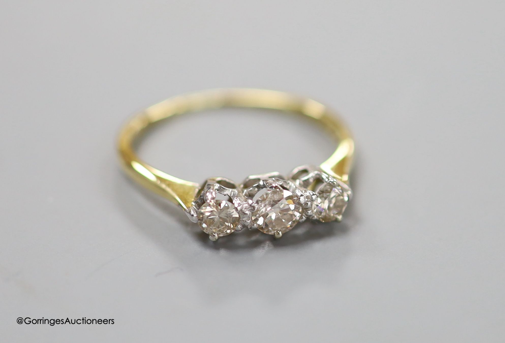 An 18ct and three stone diamond ring, size LM, gross 2.1 grams.